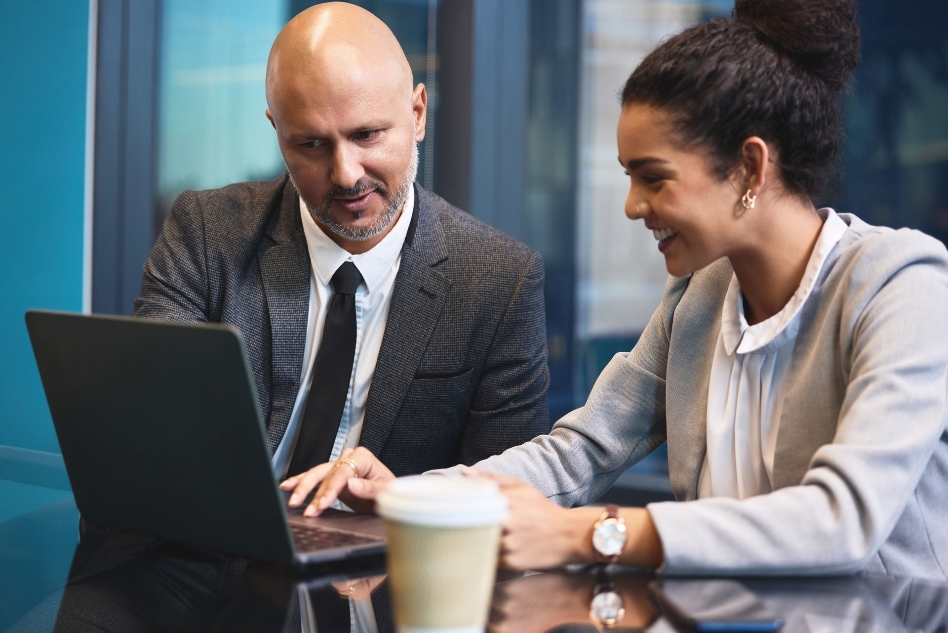 Business, people and happy in office with laptop for ideas or planning with reports or review for company finance. Partners, employees and smile in boardroom with teamwork, collaboration and feedback